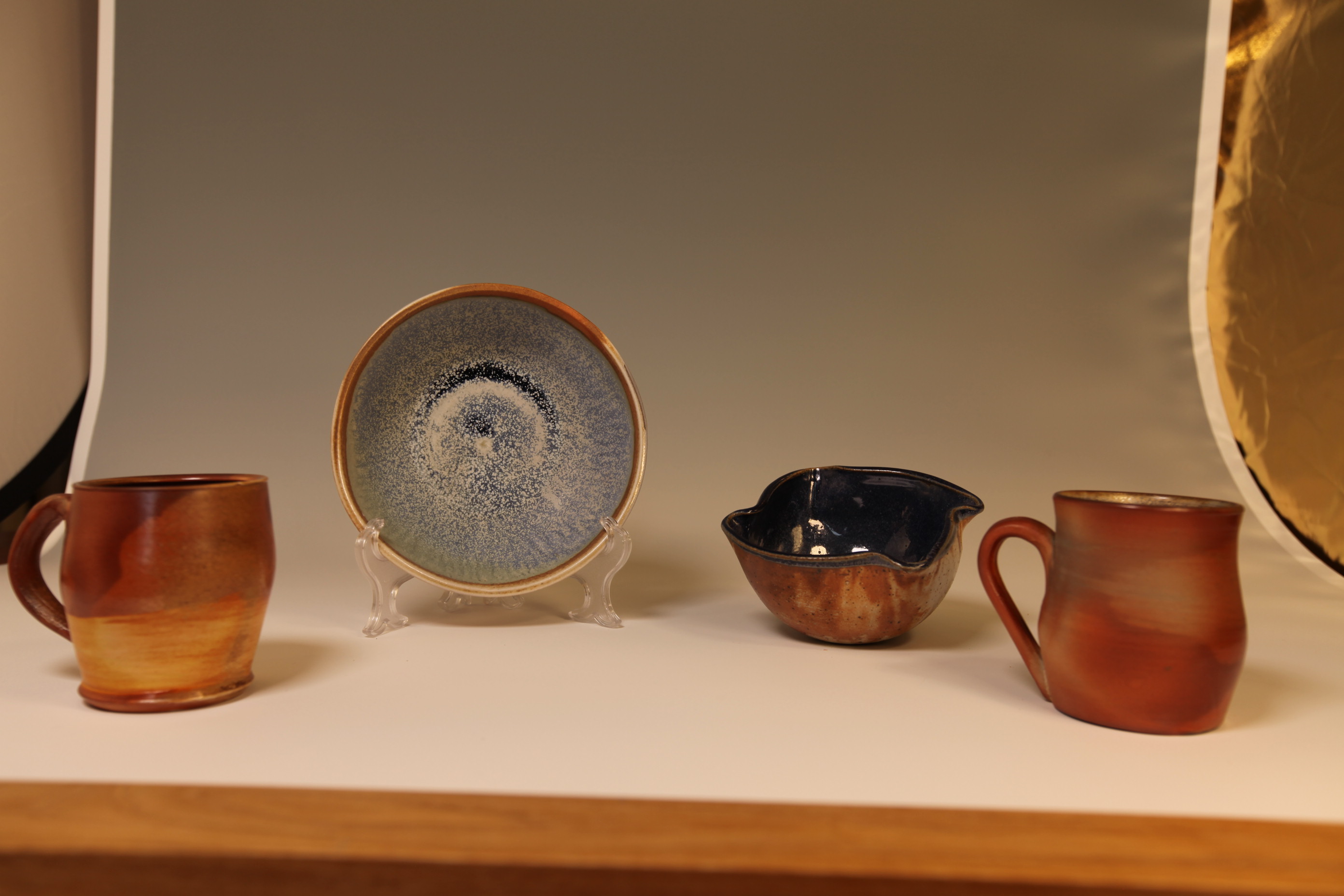 Mixed glazed ceramics — blue plate and amber mugs