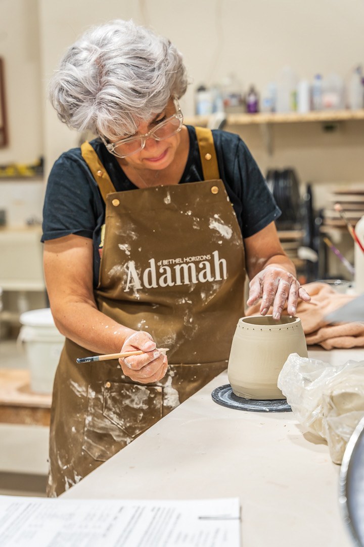 Maria decorating a piece in the studio